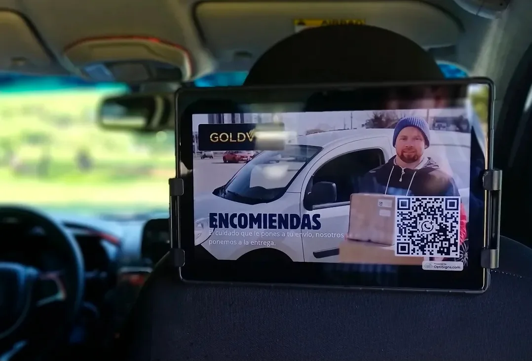Pantalla en un vehículo mostrando un aviso de servicio de encomiendas con código QR